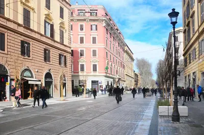 a group of people walking down a city street at House of Cardinals in Rome