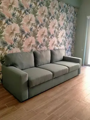 a couch in a living room with a floral wall at The green place alloggio turistico in Rome