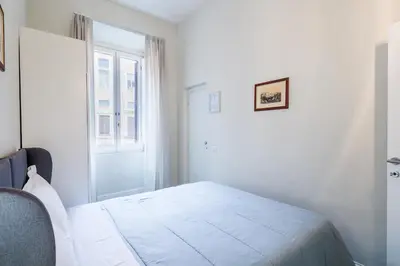 a white bedroom with a bed and a window at Prefetti 46 in Rome