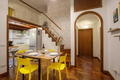 a kitchen and dining room with a table and yellow chairs at B5 Apartment Vatican in Rome