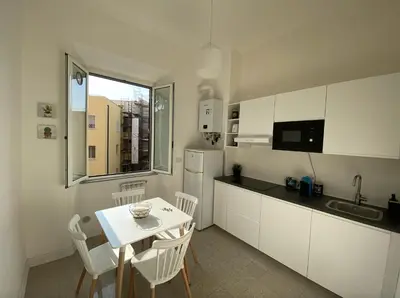a kitchen with a table and white cabinets and a table and chairs at Dew Vatican Apartment in Rome