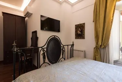 a bedroom with a bed and a desk and a television at Idyllia - Classy apartment in Vatican area in Rome