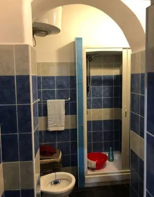 a blue tiled bathroom with a sink and a toilet at Loft Accogliente - Piazza San Giovanni in Rome