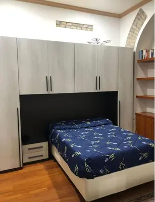 a bedroom with a bed with blue sheets and white cabinets at Loft Accogliente - Piazza San Giovanni in Rome