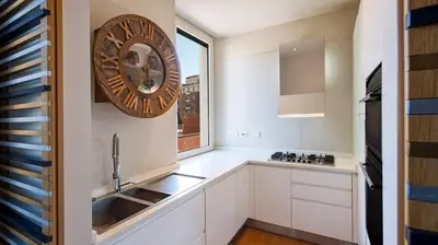 a kitchen with white cabinets and a clock on the wall at [ROMAN JEWEL] Elegant apartment near the center in Rome