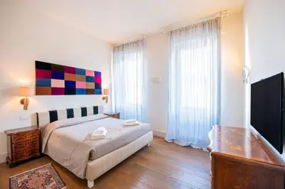 a bedroom with a bed and a dresser and a television at [ROMAN JEWEL] Elegant apartment near the center in Rome