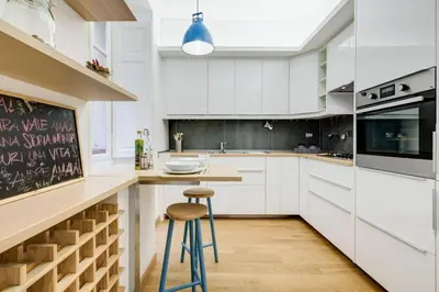 a kitchen with white cabinets and a bar with a stool at Incantevole appartamento in pieno centro a Roma in Rome