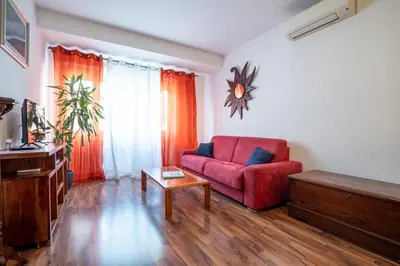 a living room with a red couch and a table at Rialto Apartment Vatican Museums in Rome
