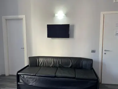 a black leather couch in a room with a tv on a wall at The Manzoni in Rome