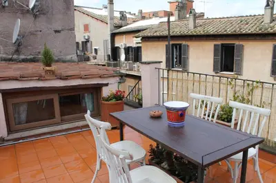 a table and two chairs on a balcony with a building at Casa Greco - Attico con terrazza, Trastevere in Rome