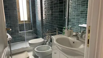 a blue tiled bathroom with a toilet and a sink at Good Time Apartment in Rome