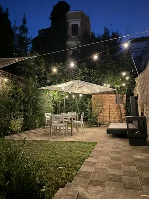 a table and chairs under an umbrella in a garden at night at Residenza Caprera in Rome