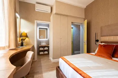 a bedroom with a bed and a desk with a chair at Royal Rooms Corso in Rome