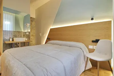 a bedroom with a white bed and a white chair at Dea Rome Suites in Rome