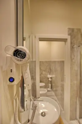 a bathroom with a hair dryer on the wall next to a sink at Dea Rome Suites in Rome