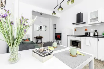 a white kitchen and living room with a table at Emily a Roma home in Rome