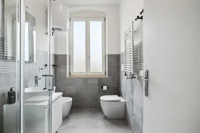 a bathroom with a toilet and a sink and a window at Limehome Rome via dei Reti in Rome
