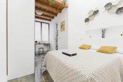 a white bedroom with a large bed with yellow pillows at Pav Suite Rome in Rome