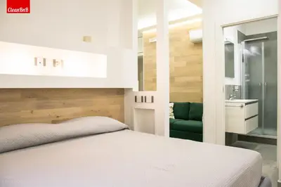 a bedroom with a white bed and a green chair at GuestHost - Largo Leopardi Modern Apartment in Rome