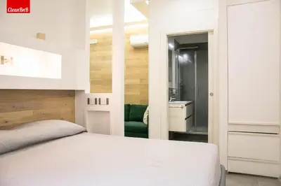 a bedroom with a white bed and a bathroom at GuestHost - Largo Leopardi Modern Apartment in Rome