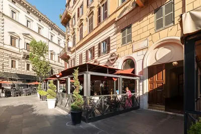a woman walking down a street next to a building at GuestHost - Largo Leopardi Modern Apartment in Rome