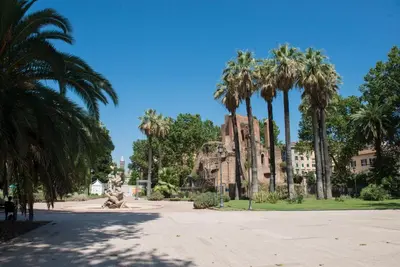 a park with palm trees and a building at Vittorio Apartment Rome in Rome