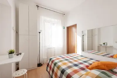 a white bedroom with a bed and a desk at central little basic apartment in Rome