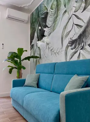 a blue couch in a living room with a painting at Avocado House - Cozy Apartment in the Heart of Rome in Rome