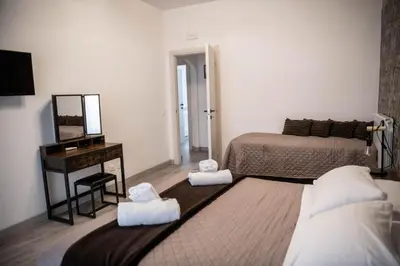 a bedroom with two beds and a desk and a mirror at Vatican Fashion Home in Rome
