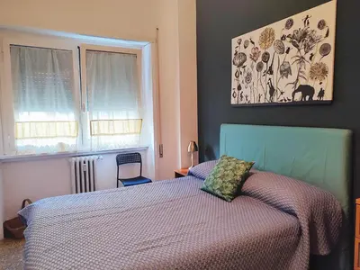 a bedroom with a bed with a blue headboard and two windows at Da Licia in Rome