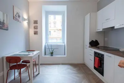 a white kitchen with a table and chairs and a window at La casa di Jojo al Ghetto in Rome