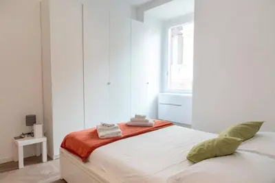 a white bedroom with a bed with an orange blanket at La casa di Jojo al Ghetto in Rome