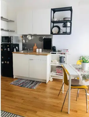 a kitchen with white cabinets and a table with chairs at A Casa di Lele in Rome