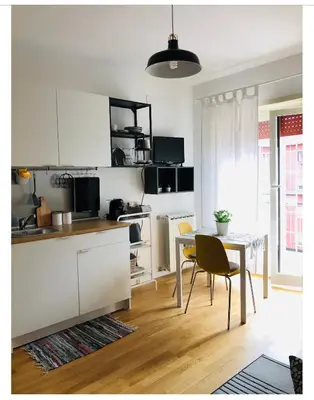 a kitchen with white cabinets and a table with chairs at A Casa di Lele in Rome