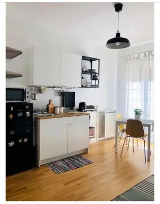 a kitchen with white cabinets and a table and a dining room at A Casa di Lele in Rome