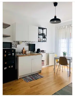 a kitchen with white cabinets and a table and a dining room at A Casa di Lele in Rome