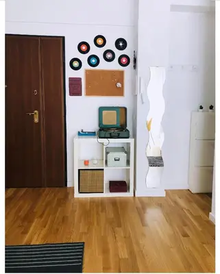 a room with a white wall and a shelf with records at A Casa di Lele in Rome