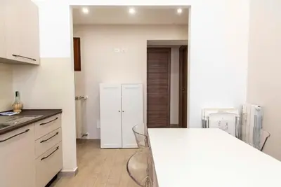 a kitchen with a white counter and chairs in it at Domus Viola in San Giovanni in Rome
