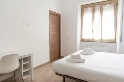 a white room with a bed and a desk and a chair at Domus Viola in San Giovanni in Rome