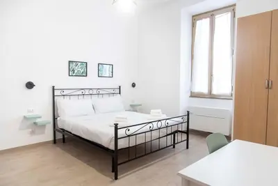 a white bedroom with a bed and a table at Domus Viola in San Giovanni in Rome
