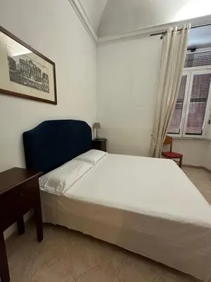a bedroom with a white bed and a blue chair at Alloggio Turistico in Rome