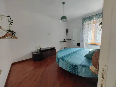 a bedroom with a bed with a blue bedspread and a window at La Casetta Azzurra in Rome