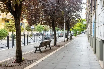 a park bench next to a tree on a sidewalk at Maison del Re - San Giovanni by RHR in Rome
