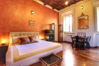 a bedroom with a large bed and a table with chairs at Trastevere Charming Romantic Loft By YourHost in Rome