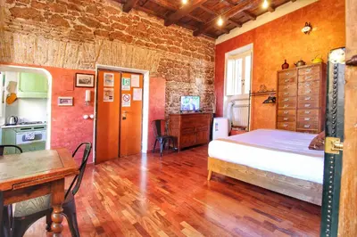 a bedroom with a bed and a table and a kitchen at Trastevere Charming Romantic Loft By YourHost in Rome