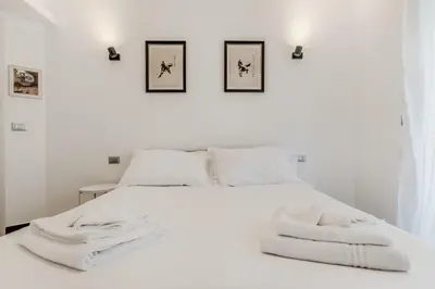 a bedroom with a white bed with two pictures on the wall at BBHOME Tiburtina Station apartment in Rome