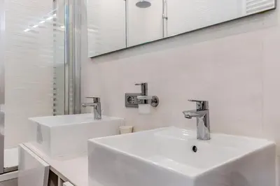 a white bathroom with two sinks and a mirror at BBHOME Tiburtina Station apartment in Rome