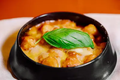 a black bowl of food with a basil leaf on top at Residenza Piranesi Boutique Hotel in Rome
