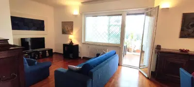 a living room with two blue chairs and a sliding glass door at appartamento panoramico su Roma in Rome