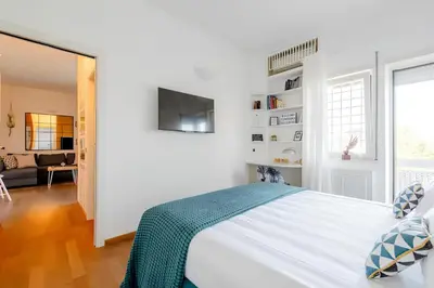 a white bedroom with a bed and a living room at Nonna Cocchina House Rome close to Vatican City in Rome